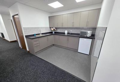Modern communal kitchen with grey cabinetry and a tiled backsplash.
