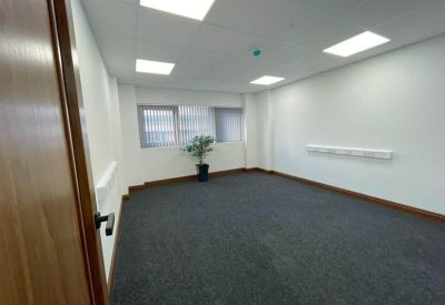 Spacious private office with grey carpet and a corner plant.
