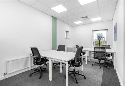 Internal four-person office suite with white desks and a green feature wall stripe.