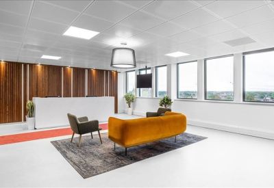 Spacious lounge area featuring a velvet mustard sofa on a textured rug near large windows.