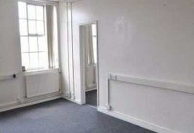 Bright corner office featuring large windows and white walls.