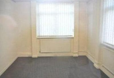 Functional office room with vertical blinds and grey carpeting.