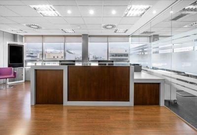Modern office kitchen with orange backsplash, coffee machine, and microwave.