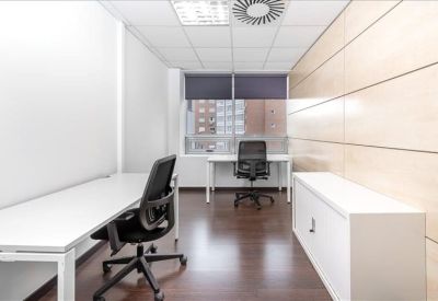 Bright workspace featuring four desks with partitions and wood-paneled walls.