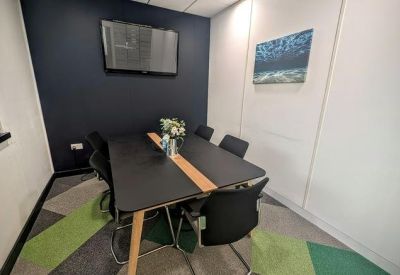 Small meeting room with a dark feature wall, wooden accented table, and green patterned carpet.