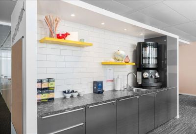 Modern office kitchen with dark grey cabinetry and a professional coffee station.
