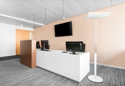 White minimalist reception desk with computer monitors and peach accent wall.