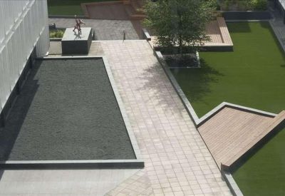Landscaped courtyard area with stone paving, green lawns, and a modern wooden seating structure.