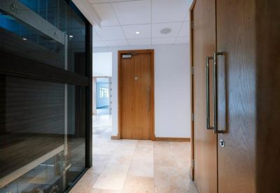 Reception hallway featuring a light wood door and large glass partition walls.