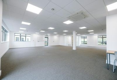 Spacious, open-plan office suite with grey carpeting and abundant natural light.