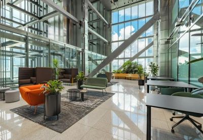 Spacious, sun-drenched coworking area with floor-to-ceiling windows and colorful lounge furniture.