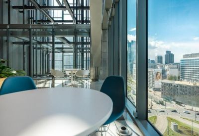 Bright window-side workstation area with white tables and blue chairs overlooking the city.