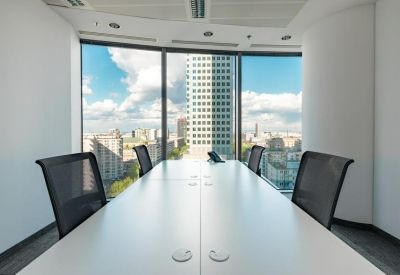 Formal boardroom with a long white table and panoramic urban skyline views.