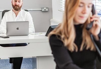 Professional focused on work in a bright office setting with white desks.