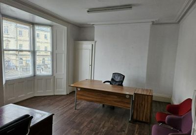 Spacious private office with a wooden desk and bay window.