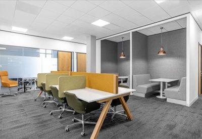 Modern coworking area with semi-private booths, yellow partitions, and olive green chairs.