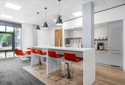 Bright kitchen breakout area with high white tables and vibrant red bar stools.