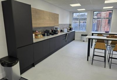Modern communal kitchen and dining area with dark cabinetry, wooden accents, and high-top tables.