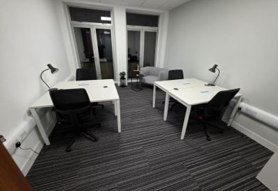 Private office suite featuring two white desks with black chairs and desk lamps.