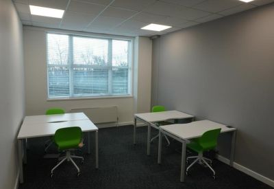 Compact private office with three white desks and vibrant green chairs.