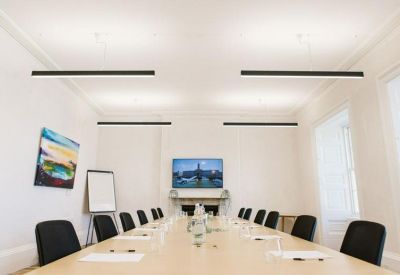 Meeting room with long table, black chairs, and wall art.