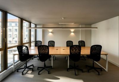 Bright conference room with a long wooden table, black mesh chairs, and large windows.