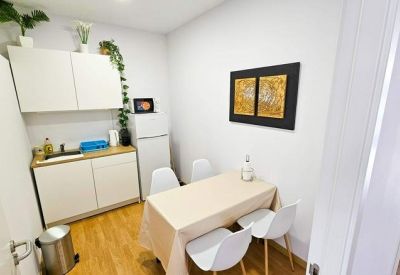 Compact kitchenette and dining area with white cabinetry and a small table.