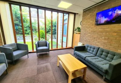 Lounge area with blue sofas, a wooden coffee table, and a brick feature wall.