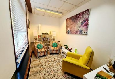 Cozy meeting room with a yellow armchair, patterned rug, and colorful wall art.