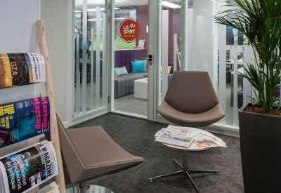 Waiting area with stylish brown lounge chairs and a magazine rack.