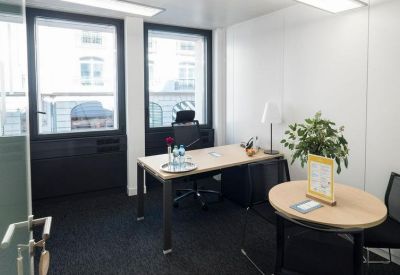 Bright private office suite with a wooden desk and a small circular meeting table.