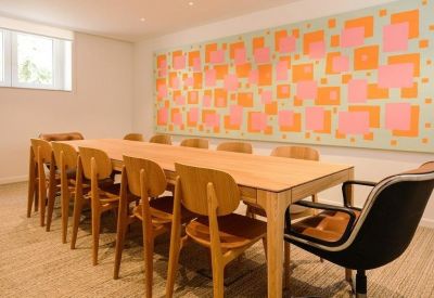 Long wooden conference table under a large colorful square-patterned art piece.