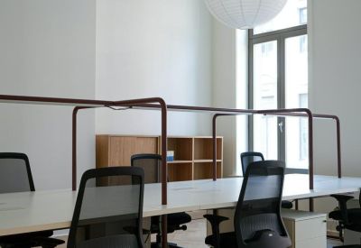 Bright open-plan workspace with multiple desks, mesh chairs, and large windows.