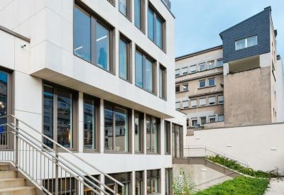 Exterior view of the white stone facade and outdoor greenery at Rue Glesener 21, Luxembourg.