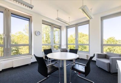 Corner meeting room with a round table, black chairs, and panoramic window views.