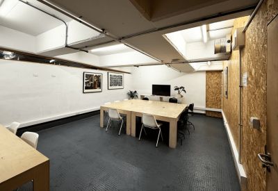 Spacious meeting room at Peckham Levels featuring a large wooden table and grey industrial flooring.