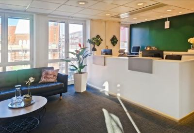 Reception area with a white front desk, green feature wall, and comfortable navy sofa.