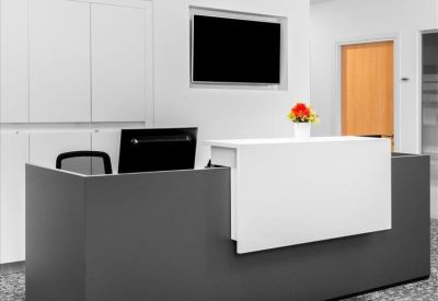 Modern dark grey and white reception desk with integrated lighting and a floral accent.