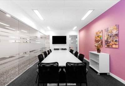 Long conference room with a pink feature wall and framed artwork.