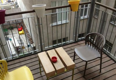 Modern balcony area with wooden decking, colorful planters, and outdoor seating.
