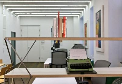 Workspace featuring a vintage typewriter on a shelf and modern office chairs.
