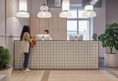 Reception area featuring a tiled desk, designer pendant lights, and indoor plants.