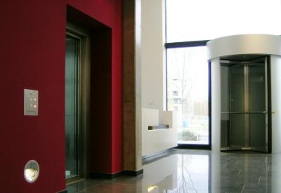 Sleek modern lobby with polished stone floors, a revolving door, and a vibrant red feature wall.
