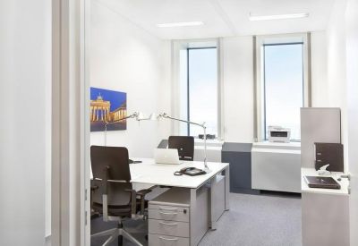 Private two-person office with white desks and a framed artwork of the Brandenburg Gate.