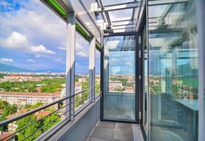 Sunlit glass-enclosed balcony overlooking the city skyline.