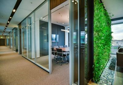 Sleek glass-walled meeting room adjacent to a vibrant green living wall.
