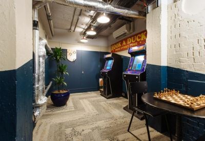 Basement breakout room with arcade machines, a chess table, and exposed ductwork.