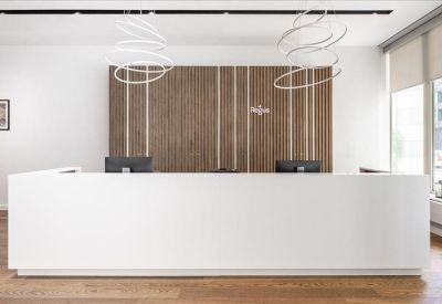 Minimalist white reception desk with a wood-slat feature wall and decorative spiral lights.