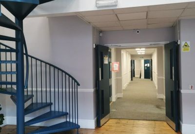 Reception area featuring a blue spiral staircase and light wood flooring leading to a corridor.