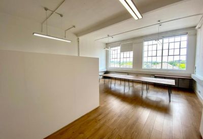 Large meeting room with long wooden tables and rows of multi-pane windows.